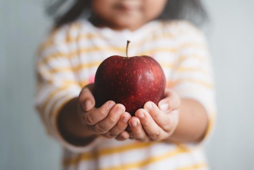 little child holding a red apple in her hand with selective and shallow depth of field blurry image