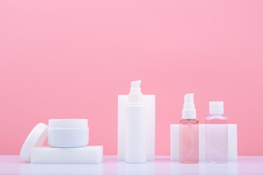 Set of cosmetic for skin care in white tubes on white table against bright pink background with copy space