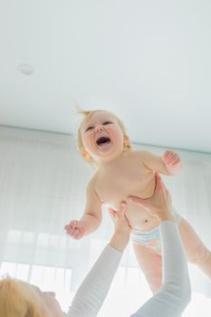 Mom, entertaining the baby, throws him up, rejoicing and having fun