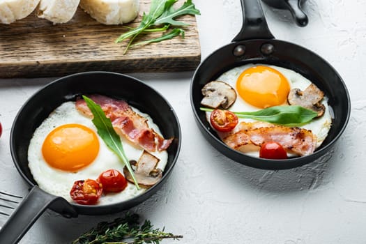 Fried eggs with cherry tomatoe and bread for breakfast in cast iron frying pan, on white background