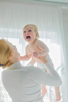 Mom, entertaining the baby, throws him up, rejoicing and having fun