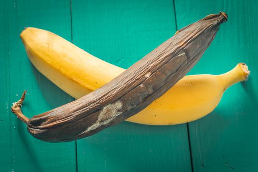 fresh and rotten banana on wooden background