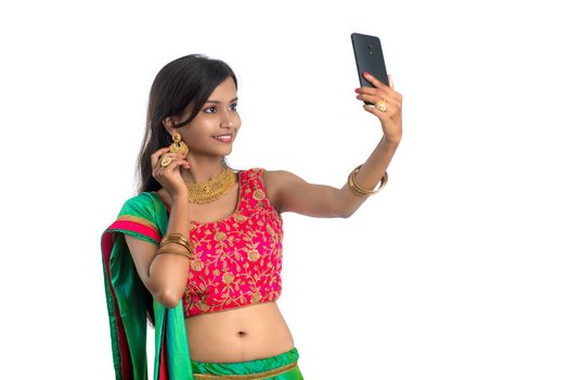 Young Indian girl using a mobile phone or smartphone, talking selfie or talking on video chat isolated on a white background
