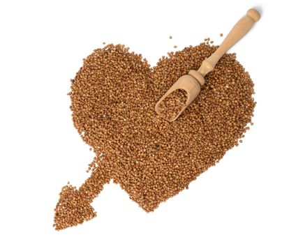 heap of uncooked buckwheat grains, top view. Groats laid out in the shape of a heart