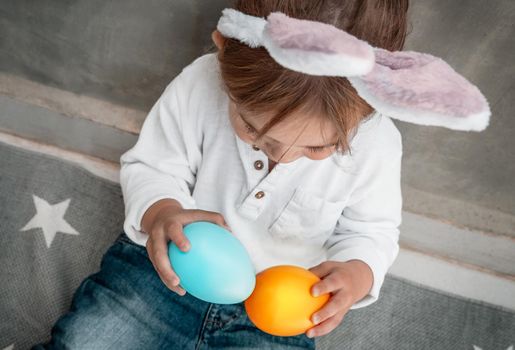 Cute Little Baby Dressed as Festive Bunny Playing with Colorful Decorative Eggs. Enjoying Happy Easter Holiday. Great Christianity Holiday.