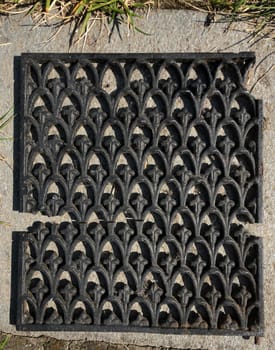 Black broken metal grid laying on the ground with patterns