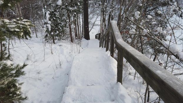 Quickly descending an old snowy wooden staircase up the hill during a morning