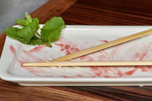 Empty rectangular plate with leftover sauce and wooden chopsticks