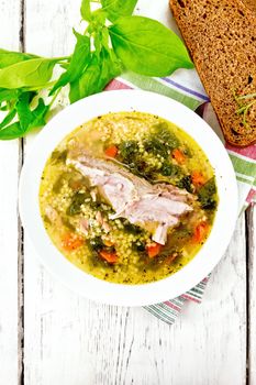Soup with couscous and spinach in plate on board top