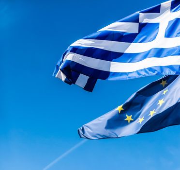 Flags of Greece and European Union on blue sky background, politics of Europe