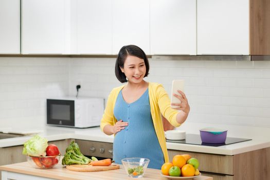 happy pregnant woman using voice command recorder on smartphone 