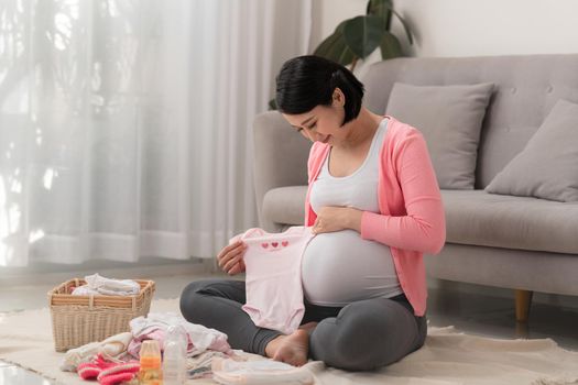 Asian mother preparing little clothes for new baby when sitting on the floor