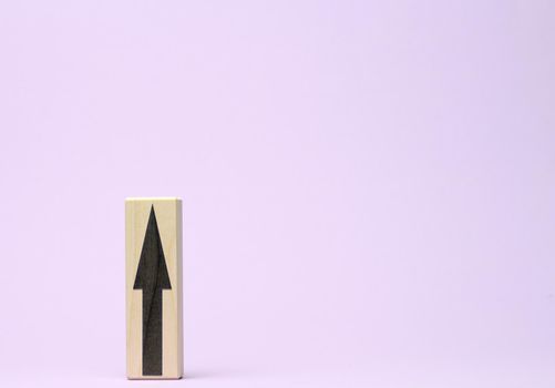 wooden block with an upward arrow on a purple background, the process of growth and achievement of goals, rising prices