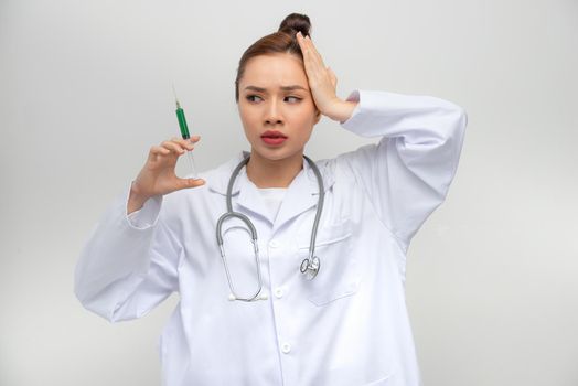 Professional doctor woman holding syringe with medical vaccine stressed with hand on head, shocked with shame and surprise face