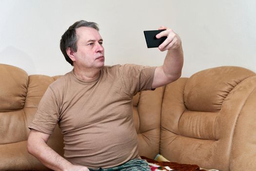 Senior citizen sitting on the couch understands the gadget, mastering smartphone