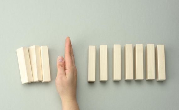 a woman's hand between the wooden blocks prevents most of it from falling