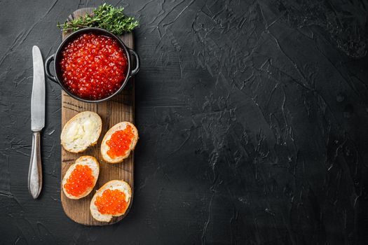 Canape toast with red caviar, on black background, top view flat lay with copy space for text