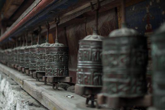 buddhist prayer wheels in a long row