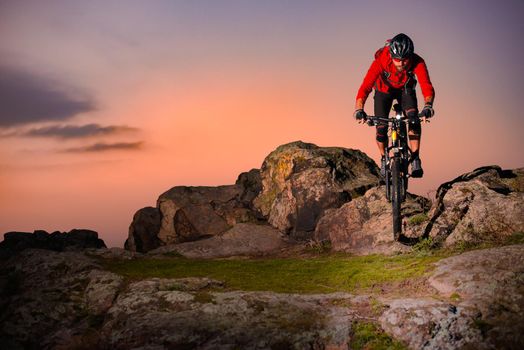 Cyclist in Red Riding Bike on the Spring Rocky Trail at Sunset. Extreme Sport and Enduro Biking Concept.