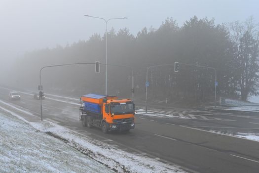 Snow plough truck. Fog and traffic in winter time.