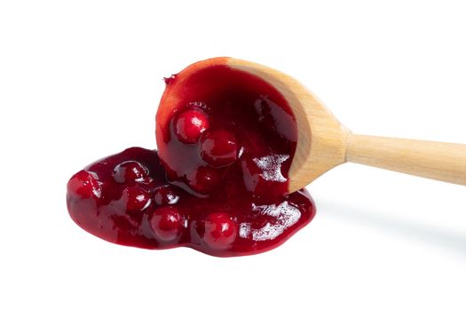 Homemade sauce made from fresh wild lingonberry drips from a spoon. Isolated on white background.