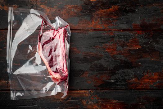 Dry aged beef marbled meat, raw fresh club beefsteak in plastic package, on old dark wooden table background, with copy space for text