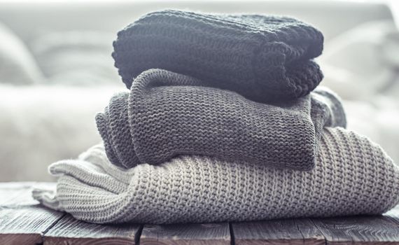 stack of cozy knitted sweaters in different colors.
