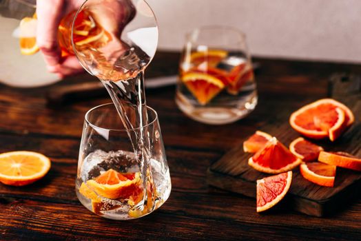 Pouring infused water with oranges into the glass