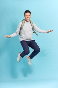 travel, tourism and people concept - happy smiling young man with backpack jumping in air over grey background