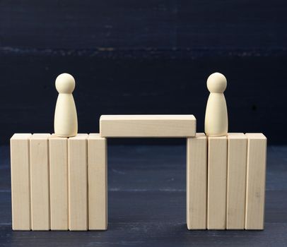 wooden figures of men on a bridge made of blocks. The concept of a dispute between opponents, dialogue