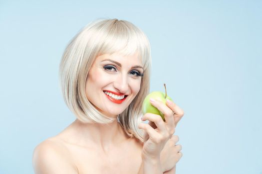 Beautiful woman eating green apple for weight loss smiling at the camera