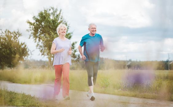 Fit and active senior couple running outdoors as exercise