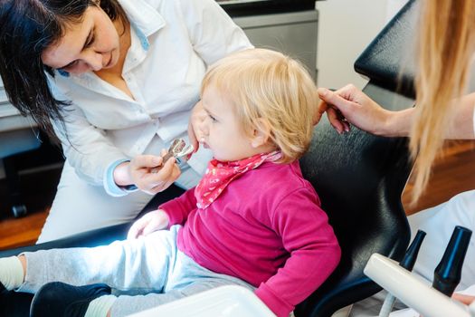 Orthodontist checking teeth of a little child