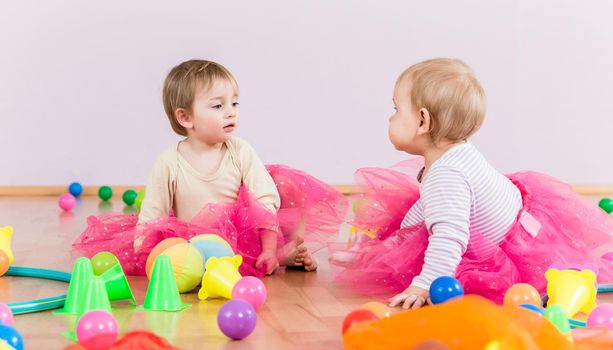 Two toddlers playing together with lots of toys