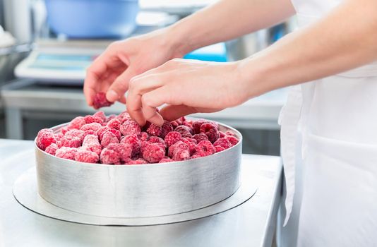 Woman confectioner making raspberry cake