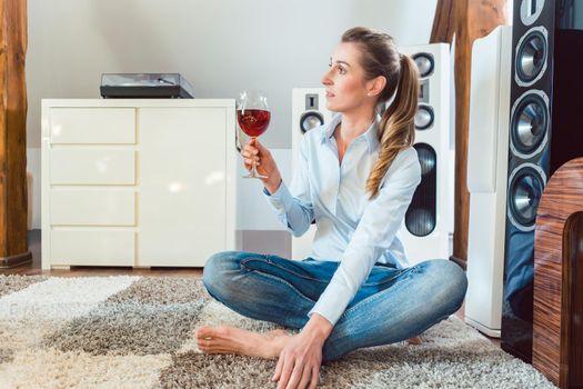 Woman having glass of wine in front of Hi-Fi speakers