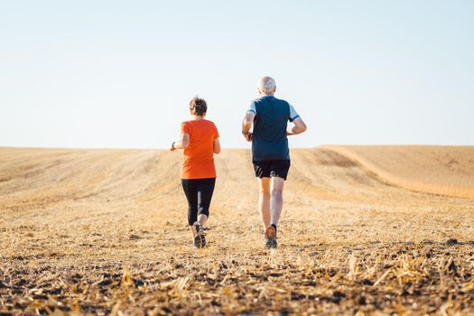 Senior woman and man running or jogging on a field