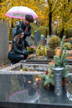 Couple in grief on a cemetery in fall