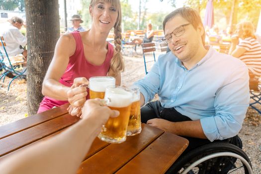 Friends in beer garden drinking, one man is in a wheelchair 