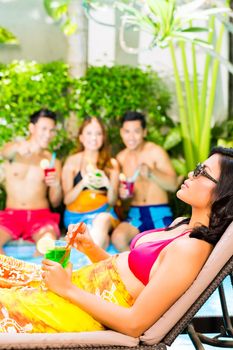 Asian friends partying at pool party in resort