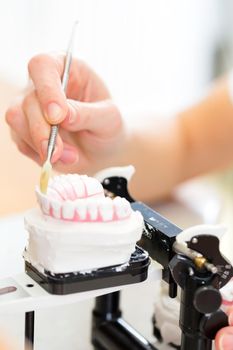 Dental technician producing denture