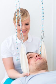 Physiotherapist exercising patient on sling table  