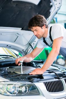 Mechanic with diagnostic tool in car workshop