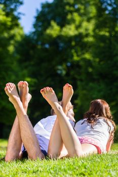 Friends laying  with crossed legs in park