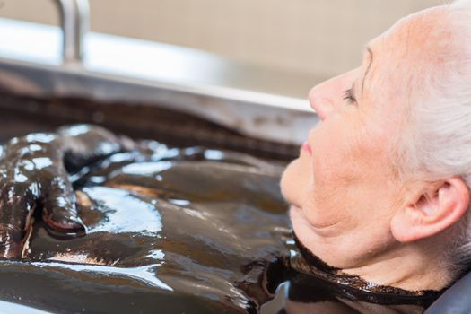 Senior woman enjoying mud bath alternative therapy
