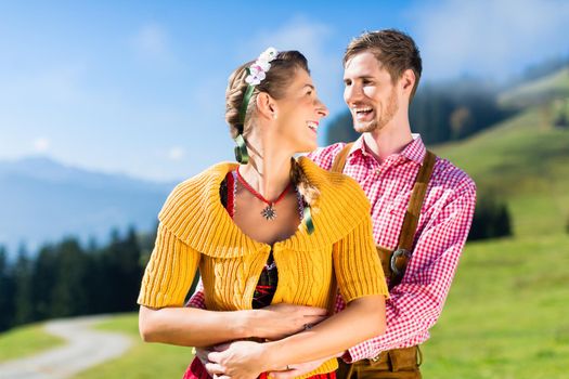Couple in Tracht on Alp mountain summit at vacation