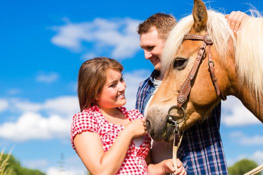 Couple petting horse on pony farm