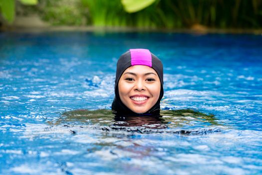 Muslim woman wearing Burkini swimwear in pool