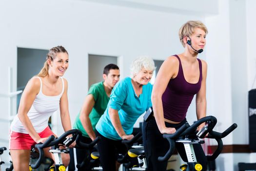 Senior people in gym spinning on fitness bike