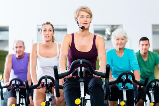 Senior people in gym spinning on fitness bike